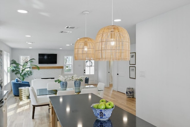 dining space featuring recessed lighting, light wood-type flooring, a brick fireplace, and visible vents