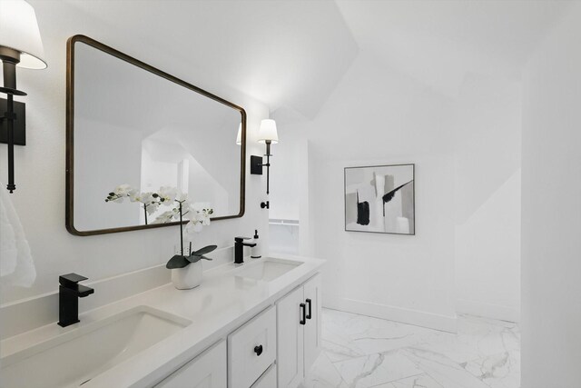 bathroom with double vanity, baseboards, marble finish floor, and a sink