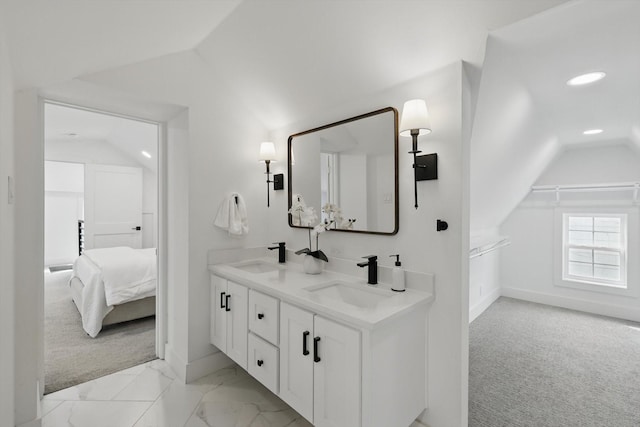 ensuite bathroom with lofted ceiling, connected bathroom, marble finish floor, and a sink