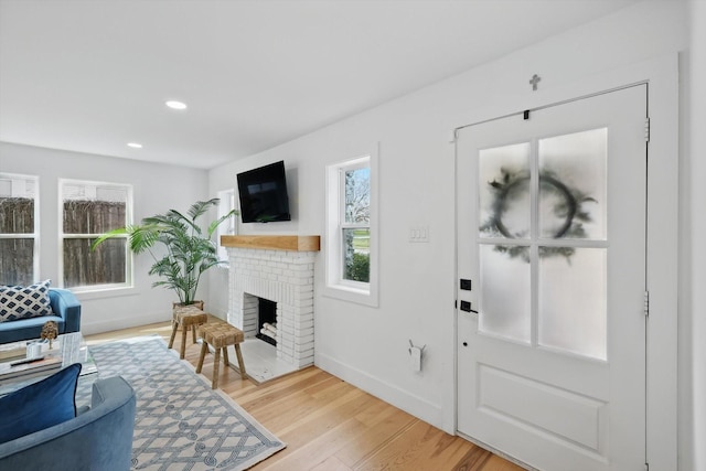 living room featuring recessed lighting, light wood-style flooring, a brick fireplace, and baseboards