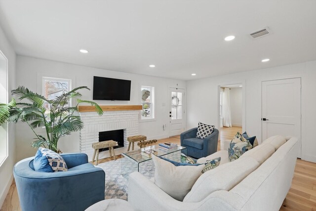 living room featuring recessed lighting, light wood-style flooring, a brick fireplace, and baseboards