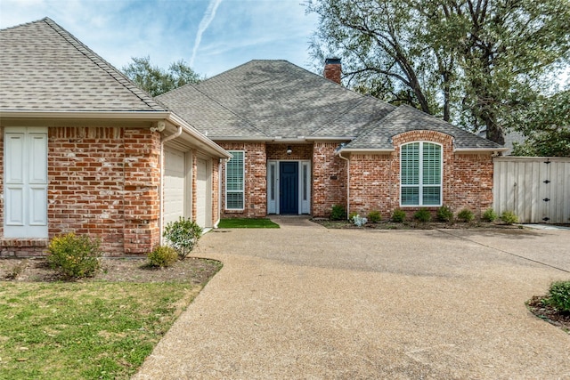 view of front of property featuring a garage, brick siding, driveway, roof with shingles, and a chimney