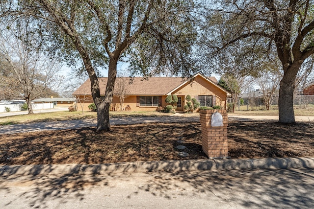 ranch-style home featuring fence and brick siding