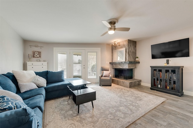 living room featuring ceiling fan, wood finished floors, baseboards, and a tile fireplace