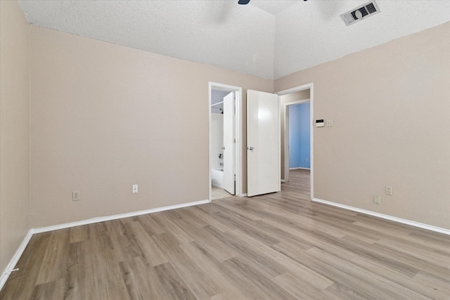 unfurnished bedroom featuring vaulted ceiling, light wood-type flooring, visible vents, and baseboards