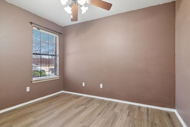 empty room with a ceiling fan, baseboards, a textured ceiling, and light wood finished floors