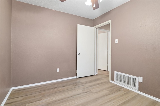 unfurnished room featuring light wood finished floors, baseboards, visible vents, a ceiling fan, and a textured ceiling