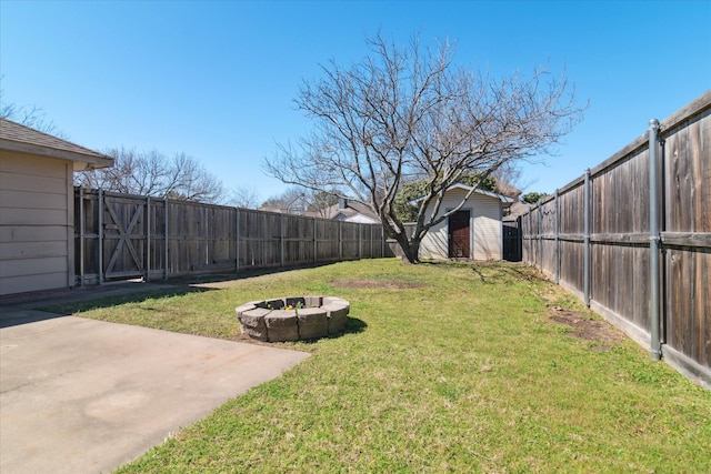 view of yard featuring an outdoor fire pit, a storage unit, a fenced backyard, and an outdoor structure