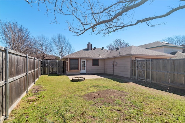 back of house with a fenced backyard, a fire pit, a lawn, a gate, and a chimney