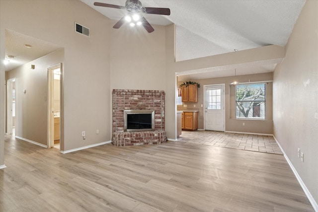 unfurnished living room featuring high vaulted ceiling, visible vents, baseboards, light wood-style floors, and a brick fireplace