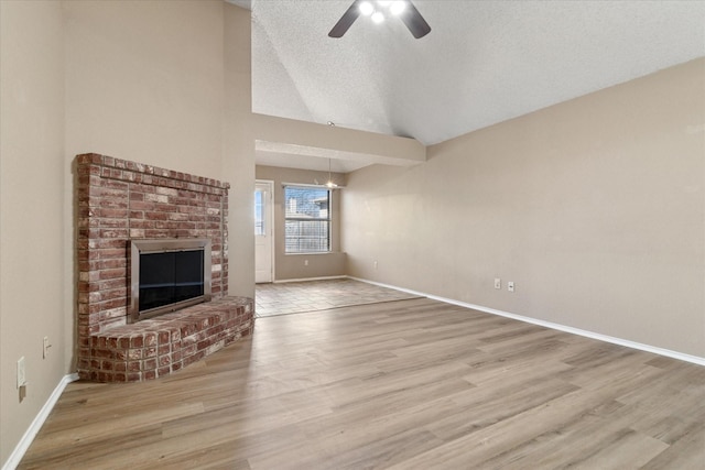 unfurnished living room with lofted ceiling, a brick fireplace, and wood finished floors