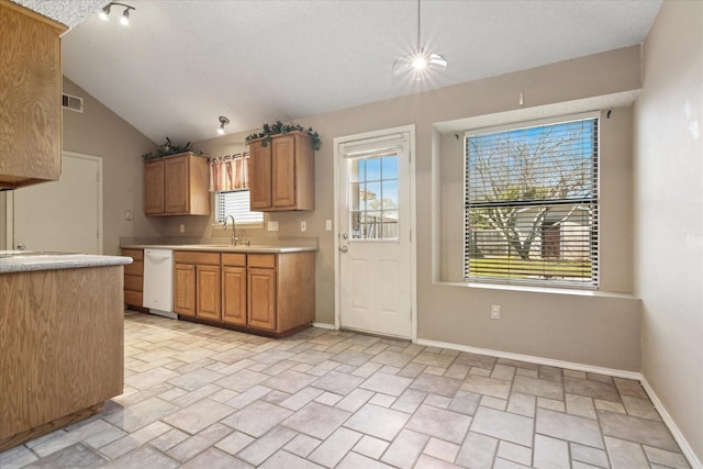 kitchen featuring lofted ceiling, a sink, baseboards, light countertops, and dishwasher