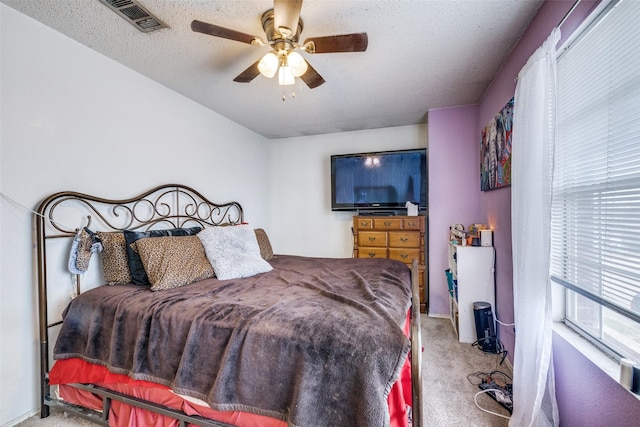 bedroom with a ceiling fan, carpet flooring, visible vents, and a textured ceiling