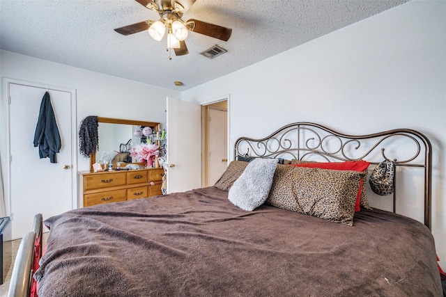 bedroom featuring a ceiling fan, visible vents, and a textured ceiling