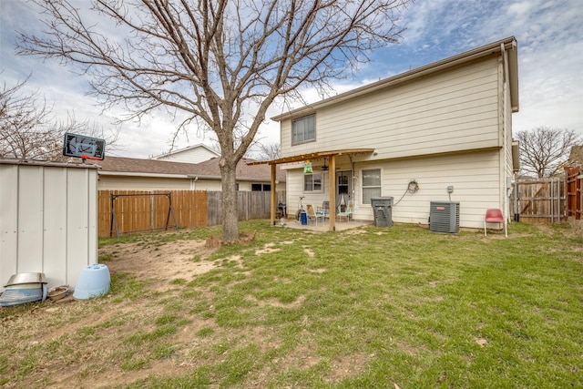 back of house with a patio, central AC unit, a fenced backyard, an outdoor structure, and a yard