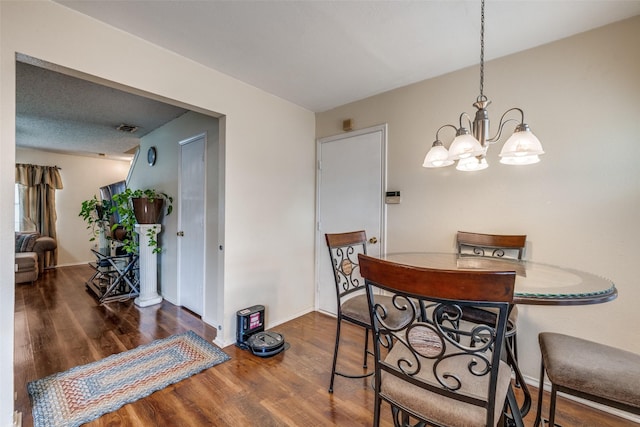 dining space featuring a chandelier, wood finished floors, visible vents, and baseboards