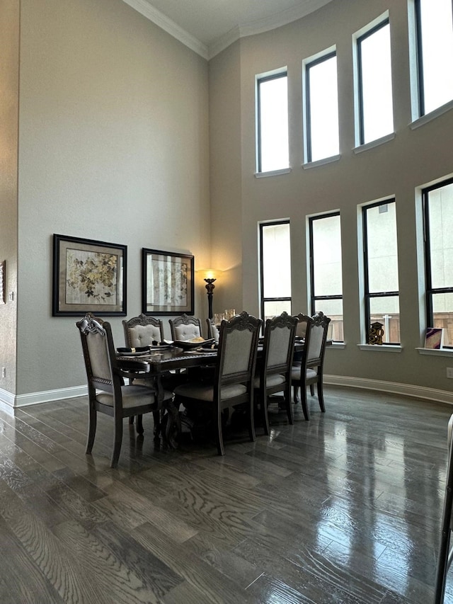 dining room featuring a high ceiling, baseboards, dark wood-style flooring, and crown molding