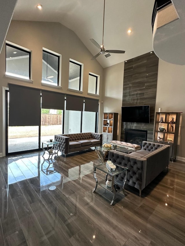 living area with a fireplace, high vaulted ceiling, a ceiling fan, and wood finished floors