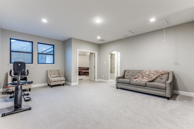 workout room featuring arched walkways, baseboards, attic access, and light colored carpet