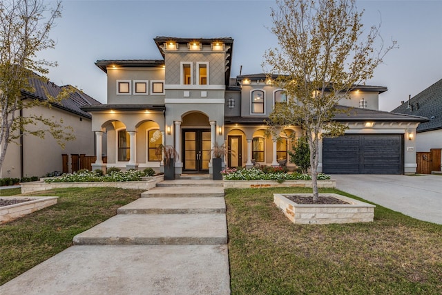 view of front of property with french doors, stucco siding, a front yard, a garage, and driveway