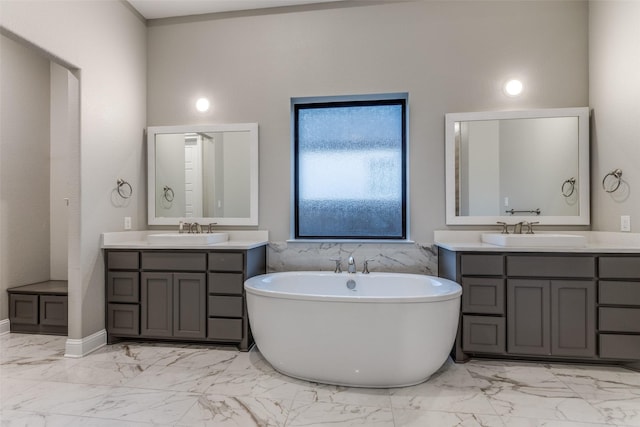 full bathroom with a freestanding tub, marble finish floor, and a sink