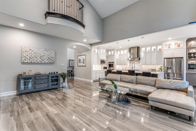 living area with arched walkways, baseboards, a high ceiling, and recessed lighting