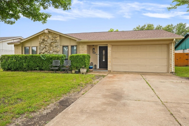 view of front of property with driveway, brick siding, an attached garage, fence, and a front yard