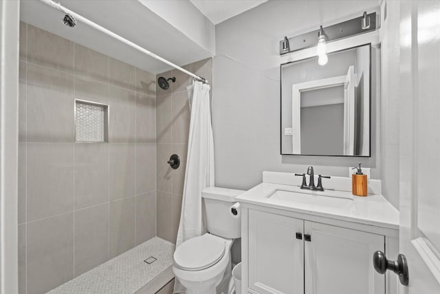 bathroom featuring a tile shower, vanity, and toilet