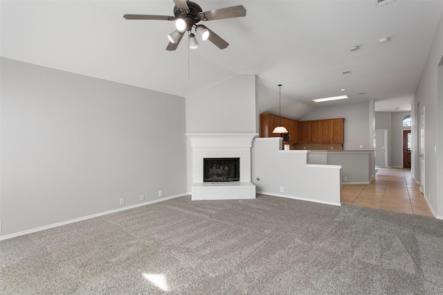 unfurnished living room featuring ceiling fan, light carpet, a fireplace, baseboards, and vaulted ceiling