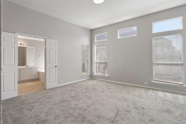 unfurnished bedroom featuring light carpet, baseboards, connected bathroom, and light tile patterned flooring