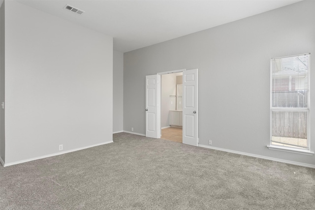 unfurnished room with a healthy amount of sunlight, baseboards, visible vents, and light colored carpet