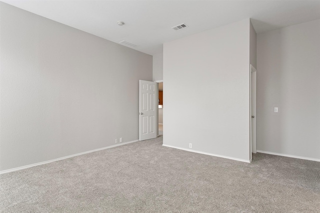 spare room with carpet floors, visible vents, and baseboards