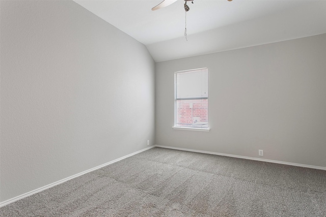 carpeted spare room featuring lofted ceiling, ceiling fan, and baseboards