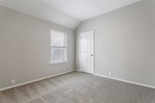 empty room featuring carpet floors, baseboards, and vaulted ceiling