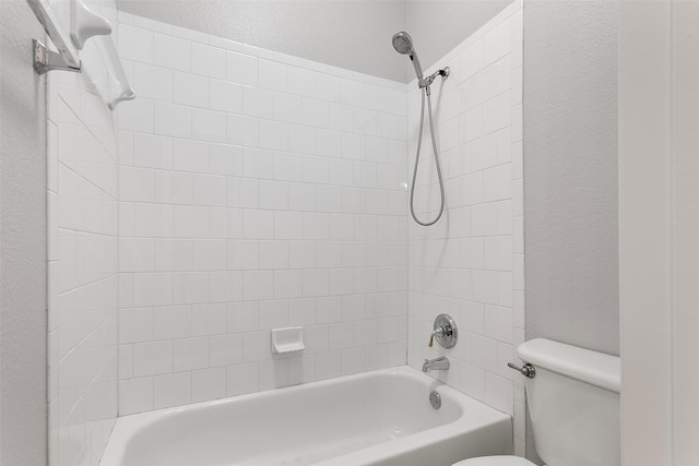 full bath with toilet, bathtub / shower combination, and a textured wall