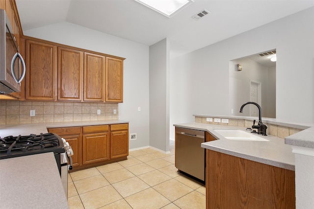 kitchen with light tile patterned flooring, stainless steel appliances, a sink, visible vents, and backsplash