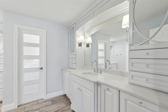 bathroom with baseboards, wood finished floors, and vanity