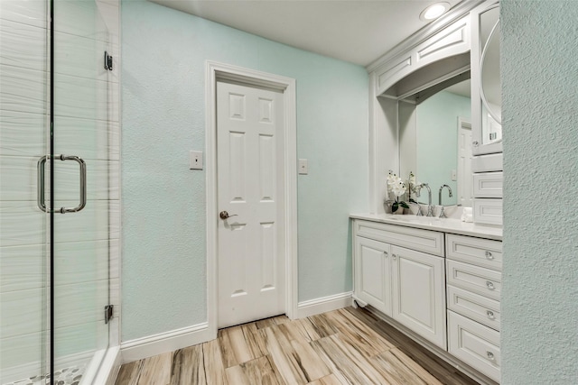full bathroom featuring baseboards, wood finished floors, vanity, and a shower stall