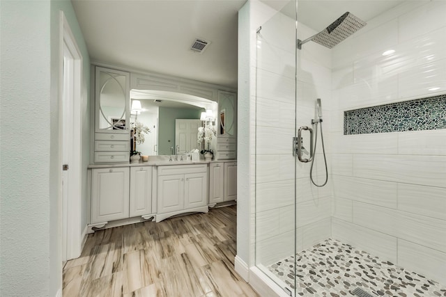 bathroom with vanity, a shower stall, and visible vents