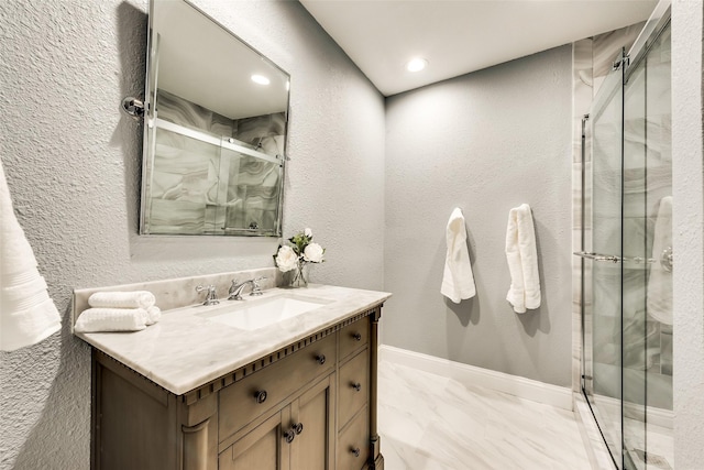 bathroom featuring vanity, marble finish floor, a textured wall, and a stall shower