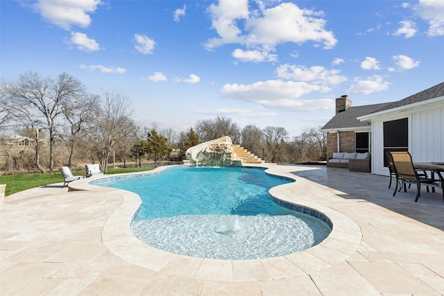 outdoor pool with outdoor lounge area, a patio, a water slide, and stairs