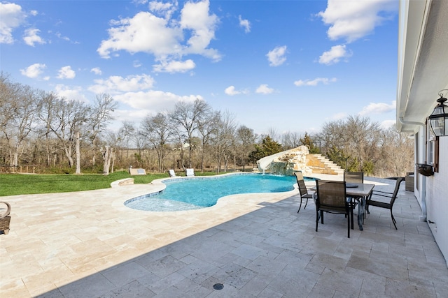 outdoor pool featuring a water slide, outdoor dining space, and a patio