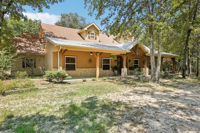 view of front of property featuring stone siding and metal roof