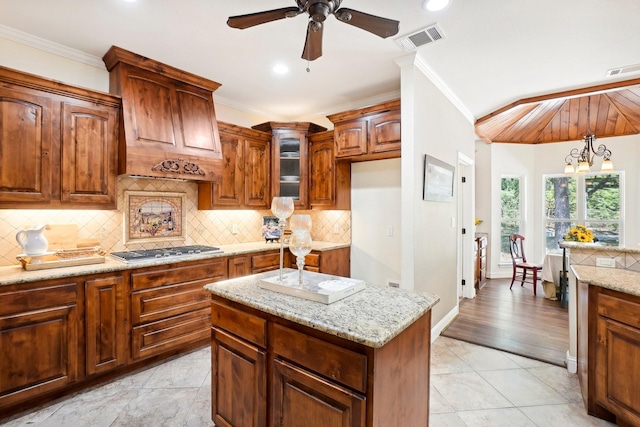 kitchen with visible vents, light stone counters, crown molding, stainless steel gas cooktop, and backsplash