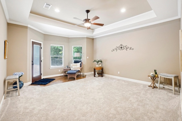 sitting room featuring carpet floors, visible vents, a tray ceiling, and ornamental molding