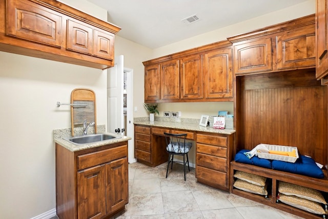 kitchen featuring brown cabinets, visible vents, a sink, and baseboards