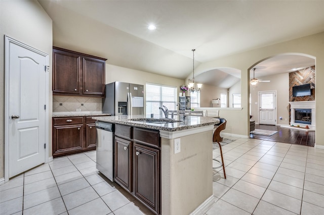 kitchen with light tile patterned floors, appliances with stainless steel finishes, a kitchen bar, and a sink