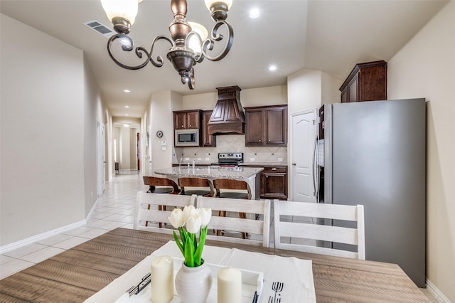 kitchen featuring visible vents, dark brown cabinets, appliances with stainless steel finishes, an inviting chandelier, and custom exhaust hood