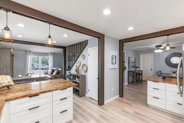 kitchen featuring beam ceiling, white cabinets, light wood-style floors, and wood counters