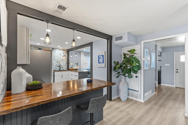 kitchen featuring visible vents, a peninsula, light wood-style flooring, and butcher block counters